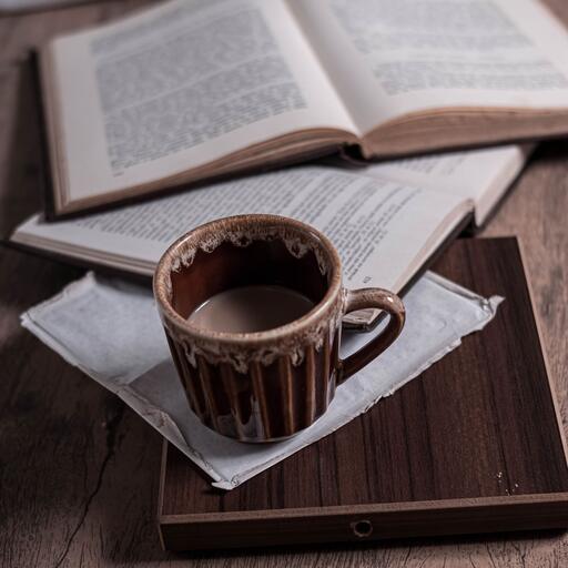 A coffee cup on an open book, unprocessed: the photo the 4 machines in this family start from.